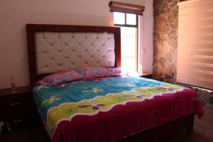 a bedroom with a large bed with a floral bedspread at La Cuadra Cabaña 2 in Zacatlán