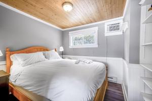1 dormitorio con cama blanca y cabecero de madera en Lakeside Serenity Retreat #10, en West Kelowna