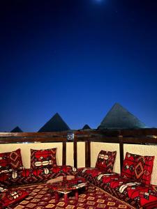 eine Terrasse mit Kissen, einem Tisch und den Pyramiden in der Unterkunft Pyramids Era View in Kairo