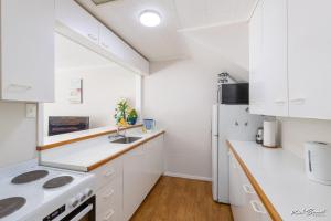 a kitchen with white cabinets and a white refrigerator at 5 bedroom modern house, private spacious backyard in Lower Hutt