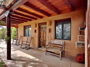 a porch of a house with chairs and a door at El Otro Tierra in Santa Fe