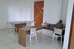 a person sitting at a desk in a room with chairs at Apartamento na Ponta Negra, 2 quartos, sendo uma suite in Manaus