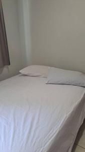 a bed with white sheets and pillows on it at Apartamento na Ponta Negra, 2 quartos, sendo uma suite in Manaus