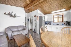 Cozy Cottage by the Lakeshore #4 في West Kelowna: مطبخ وغرفة معيشة مع طاولة وأريكة