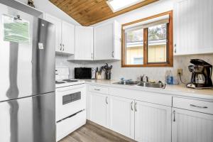 une cuisine avec des armoires blanches et un réfrigérateur en acier inoxydable dans l'établissement Cozy Cottage by the Lakeshore #4, à West Kelowna
