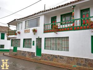 ein weißes Gebäude mit grünen Türen und Fenstern in der Unterkunft Hotel Villa de Mongui in Monguí