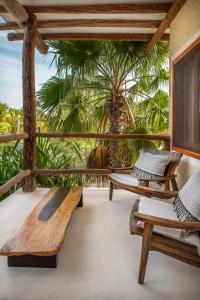 a porch with wooden benches and a palm tree at Hotel Mawimbi in Holbox Island