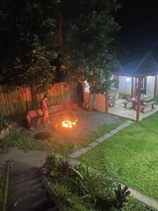 un hombre sentado en un sofá alrededor de un fuego en un patio en Sítio Domingos Martins, en Domingos Martins
