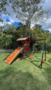 un parque infantil con un tobogán naranja en el césped en Sítio Domingos Martins, en Domingos Martins