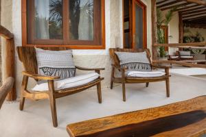 - un ensemble de chaises assises sur une terrasse couverte dans l'établissement Hotel Mawimbi, à Holbox