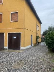 ein gelbes Gebäude mit zwei Garagentüren und einer Einfahrt in der Unterkunft Casa Oasi in Seriate