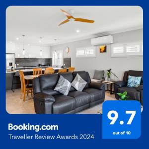 a living room with a black couch and a kitchen at Luxurious Lakefront on Franklin Island in Victor Harbor