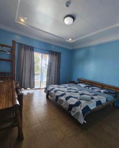 ein blaues Schlafzimmer mit einem Bett und einem Fenster in der Unterkunft 囍潜Side Effects Dive Resort Dauin in Dauin