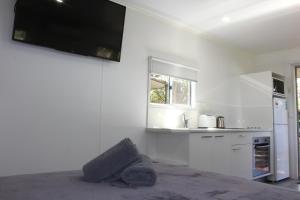 cocina blanca con TV de pantalla plana en la pared en Huntsville Caravan Park en Maryborough