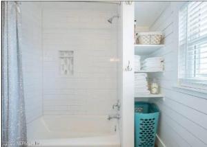 a white bathroom with a shower and a bath tub at Freshly Renovated Oceanfront Gem Near St Augustine in Ponte Vedra Beach