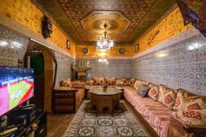 een woonkamer met een bank en een tv bij Dar Zerbtana Apartment in Fès