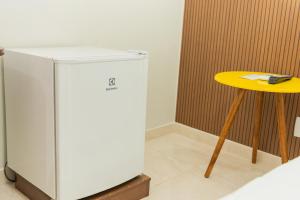 a small refrigerator and a yellow table in a room at Hotel Fernandão in Pouso Alegre