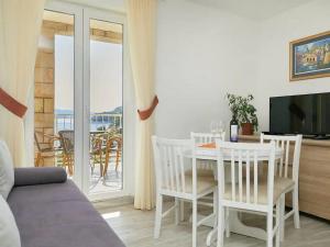 ein Wohnzimmer mit einem Tisch, Stühlen und einem TV in der Unterkunft Apartments by the sea Sobra, Mljet - 22327 in Babino Polje