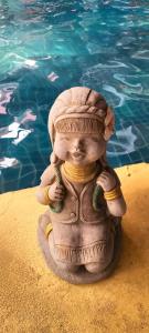 uma estátua sentada na areia ao lado de uma piscina em Lanna Boutique Resort em Chiang Mai