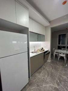 eine Küche mit einem weißen Kühlschrank und einem Tisch in der Unterkunft 2+1في اسبارتا كولي in Avcılar