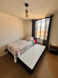 Habitación pequeña con cama y ventana en Depto piso 6 frente al mar, en Antofagasta