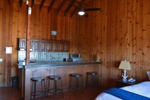 una cocina con paredes de madera y un bar con taburetes en Hotel Quintas Papagayo, en Ensenada