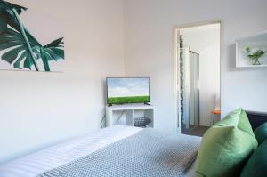 Cosy and Bright Studio Next to Westmead Hospital في سيدني: غرفة نوم بيضاء فيها سرير وتلفزيون