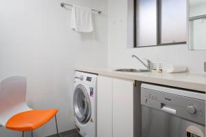 ein Badezimmer mit einer Waschmaschine und einem Waschbecken in der Unterkunft Cosy and Bright Studio Next to Westmead Hospital in Sydney