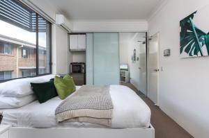 Cosy and Bright Studio Next to Westmead Hospital في سيدني: غرفة نوم بسرير ابيض مع مخدات خضراء