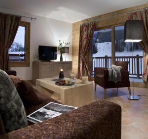 een woonkamer met een bank en een tafel bij CGH Résidences & Spas Les Chalets De Laÿssia in Samoëns