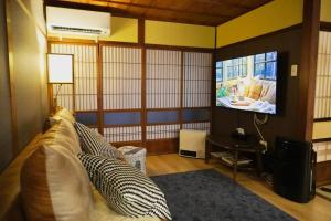 a living room with a couch and a tv at Karin House in Takayama