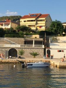 a small boat in the water next to a building at Apartments Kaja in Rab