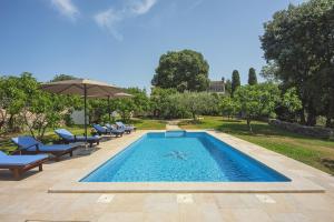 einen Pool mit Stühlen und einem Sonnenschirm in der Unterkunft Family friendly house with a swimming pool Valtura, Pula - 22734 in Pula
