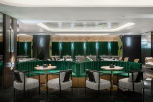 a restaurant with green walls and tables and chairs at R Royalss Hotel, Chengdu Chunxi Road Taikooli Tianfu in Chengdu