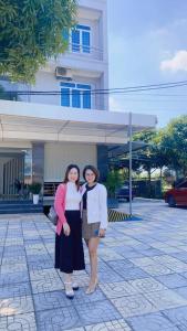 twee vrouwen staan voor een gebouw bij Amazon Hotel in Vinh