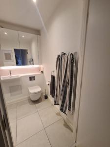 a white bathroom with a toilet and a sink at Cozy Urban Retreat in London in London