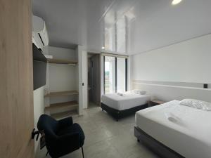 HOSTAL DEL LLANO في فيلافيسينسيو: غرفة نوم بسريرين وكرسي فيها