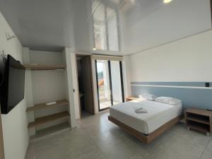a white bedroom with a bed and a window at HOSTAL DEL LLANO in Villavicencio