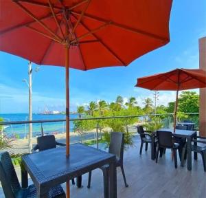 a patio with tables and chairs and red umbrellas at Hotel Almendros in San Andrés