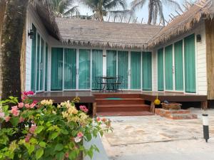 a house with green windows and a table and flowers at Nov Koh Kong Resort in Phumĭ Srê Thmei