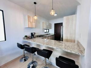 Una cocina con una encimera con taburetes. en Hermosa casa a 2 min de la playa by PartnerHost, en La Florida 12 fotos más