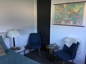 Habitación con 2 sillas azules y un mapa en la pared. en Cozy stylish studio, en Wanaka