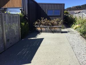 a sidewalk next to a house with a fence at Cozy stylish studio in Wanaka
