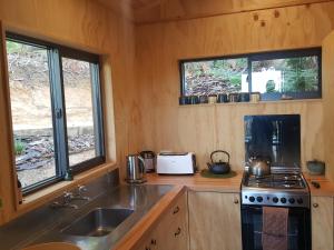a kitchen with a sink and a stove and two windows at Yurt retreat in Pangatotara