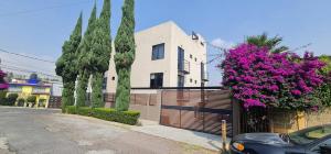 een huis met een hek en paarse bloemen bij LUXURY STUDIOS AT CASONA 46 in Mexico-Stad