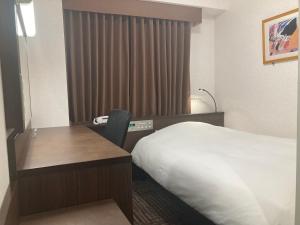 Hotel Alpha-One Yamaguchi Inter في ياماغوتشي: غرفة في الفندق مع سرير ومكتب