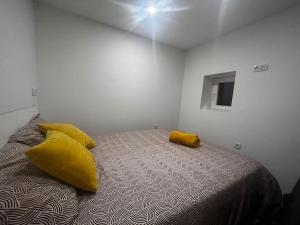a bedroom with a bed with yellow pillows on it at Flat da Kaká in Maia