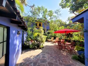 un patio con mesas, sillas y una sombrilla roja en Estrellita's Bed & Breakfast en Ajijic