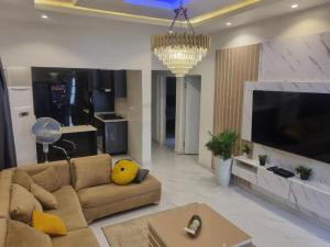 uma sala de estar com um sofá e uma televisão grande em Shagari Estate Prestige 3-Bedroom Apartments. em Lagos