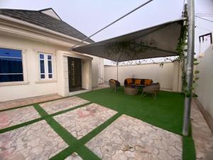 um pátio com um sofá e um guarda-chuva em Shagari Estate Prestige 3-Bedroom Apartments. em Lagos
